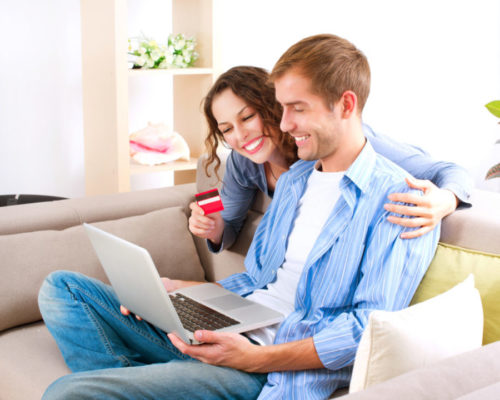 A smiling couple using their credit card to shop online.