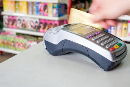 A credit card being swiped through a payment terminal at a supermarket.