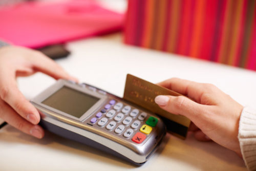 A woman swiping her credit card through a payment terminal at a retail store.