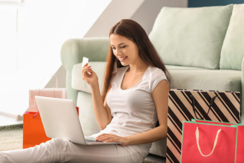 A woman using her laptop to shop online while holding her credit card.