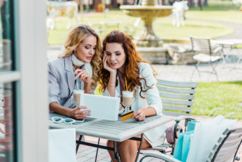 A person pays for themself and a friend with a credit card at a cafe.