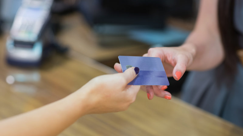 A woman handing over her credit card to a store clerk.