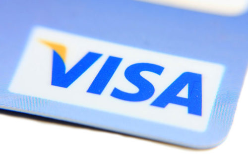 A closeup of the corner of a credit card shows the Visa logo.