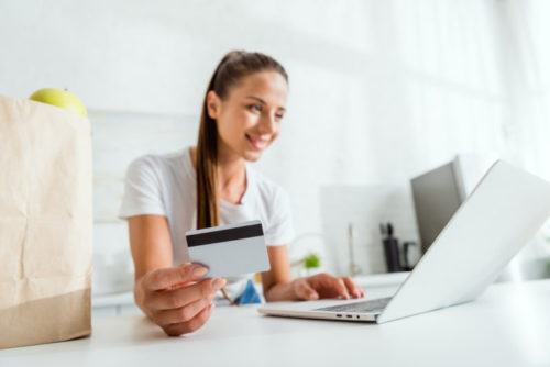 A woman shopping online with her credit card in her hand.
