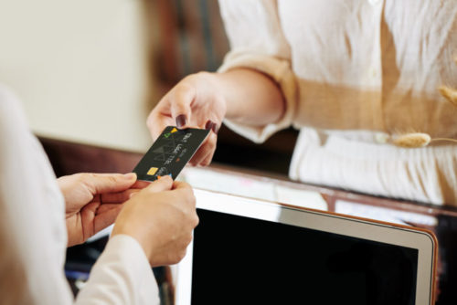 A person handing over their credit card to a store clerk.