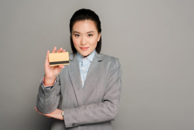 A person in business attire holding up a credit card.