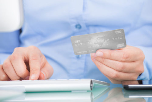 A close up of a man typing his credit card information on a keyboard.