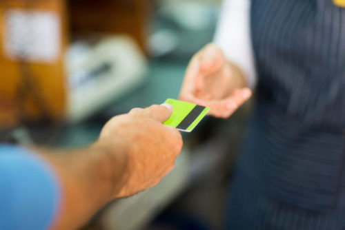 A man hands a store clerk his credit card.