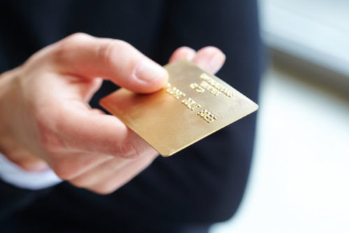 A closeup of a businessman's hand holding a credit card.