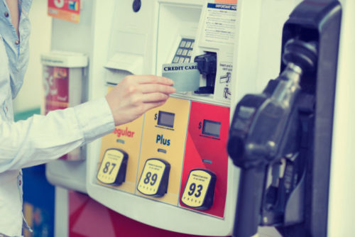 A woman paying at a gas pump with her credit card.