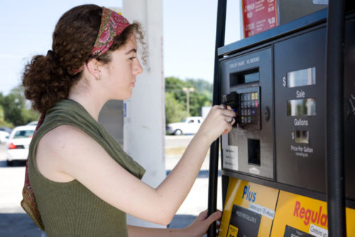 A woman paying at a gas pump with her credit card.