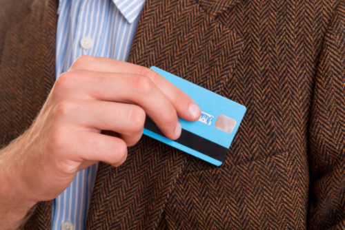 A man placing a credit card in the pocket of his jacket.