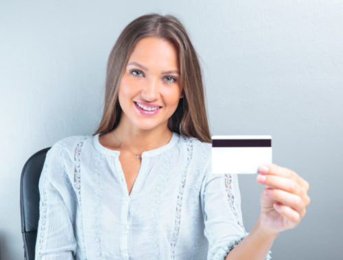 A smiling woman holding her credit card.