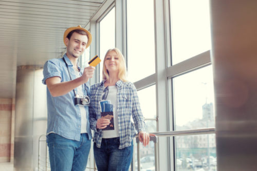 A traveling couple looking at their credit card and smiling.