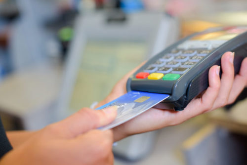 A store clerk swipes a credit card into a payment terminal.