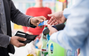 A person in business attire hands their credit card over to a store clerk.