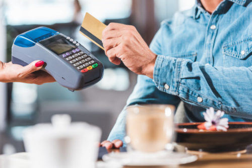 A person swiping a credit card through a payment terminal.