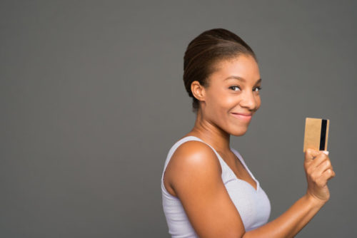 A smiling person holding a credit card.