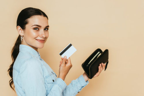 A person holds up a credit card which they have just pulled out of their wallet.