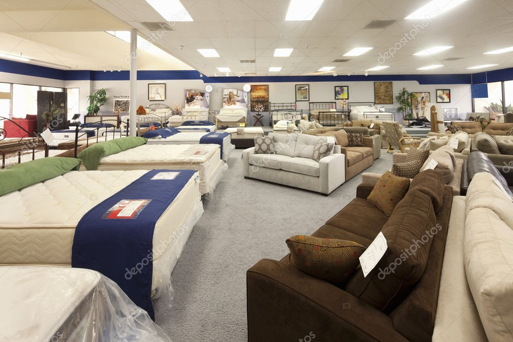 The interior of a furniture store includes multiple beds and couches.
