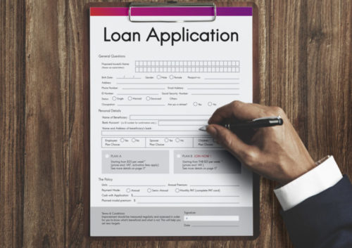 A closeup of a person filling out a document labeled "loan application."