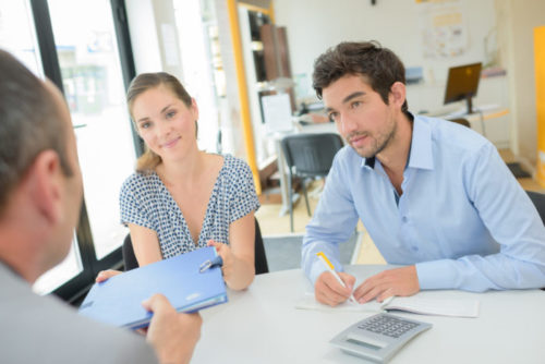 A person and their co-borrower sitting at a loan officer's desk for a meeting.