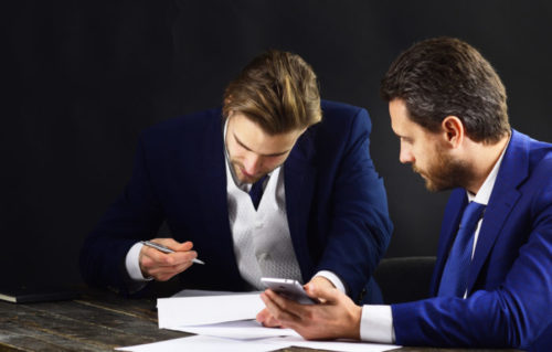 A person just about to sign a loan agreement while a loan agent sits next to them.