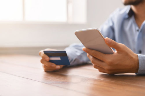 A person holding their smartphone in one hand and a credit card in the other