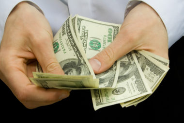 A closeup of someone's hands handling money.