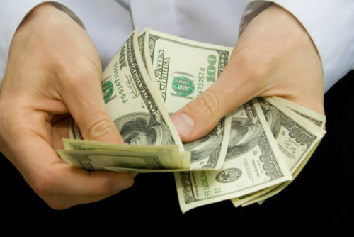 A closeup of someone's hands handling money.