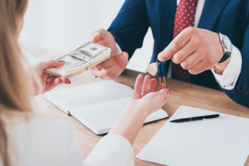 A loan officer takes collateral in the form of car keys from a person while extending them loan money.