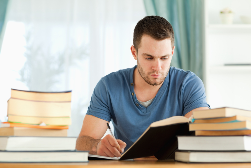 A person reading and taking notes at their desk.