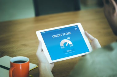 A person holding a tablet, displaying a credit score app.