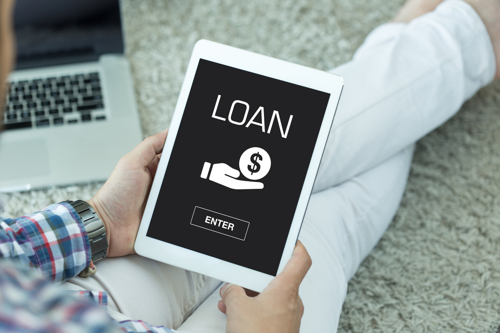 A person holding a tablet displaying a screen that reads "loan."