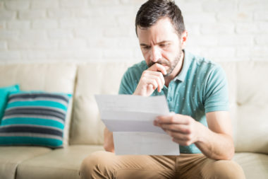A person looks worried as they read some financial documents.