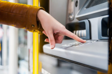 A closeup of a person's hand entering their pin at an ATM.