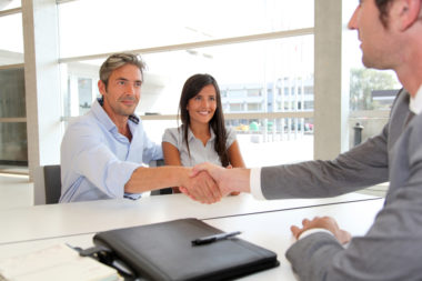 A couple shakes the hand of a banker.