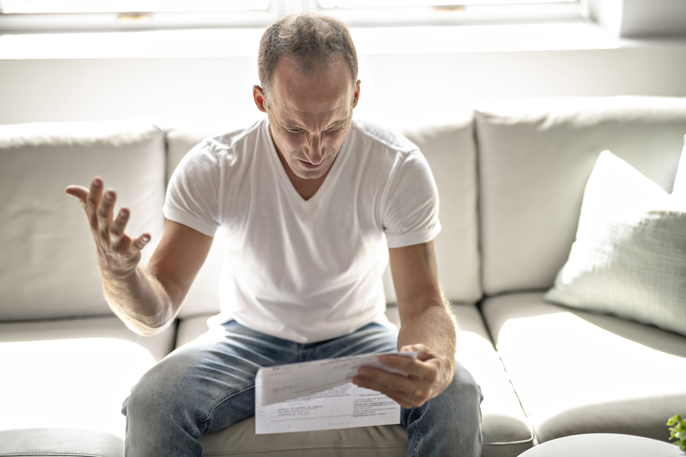 A person looks agitated while reviewing financial documents.