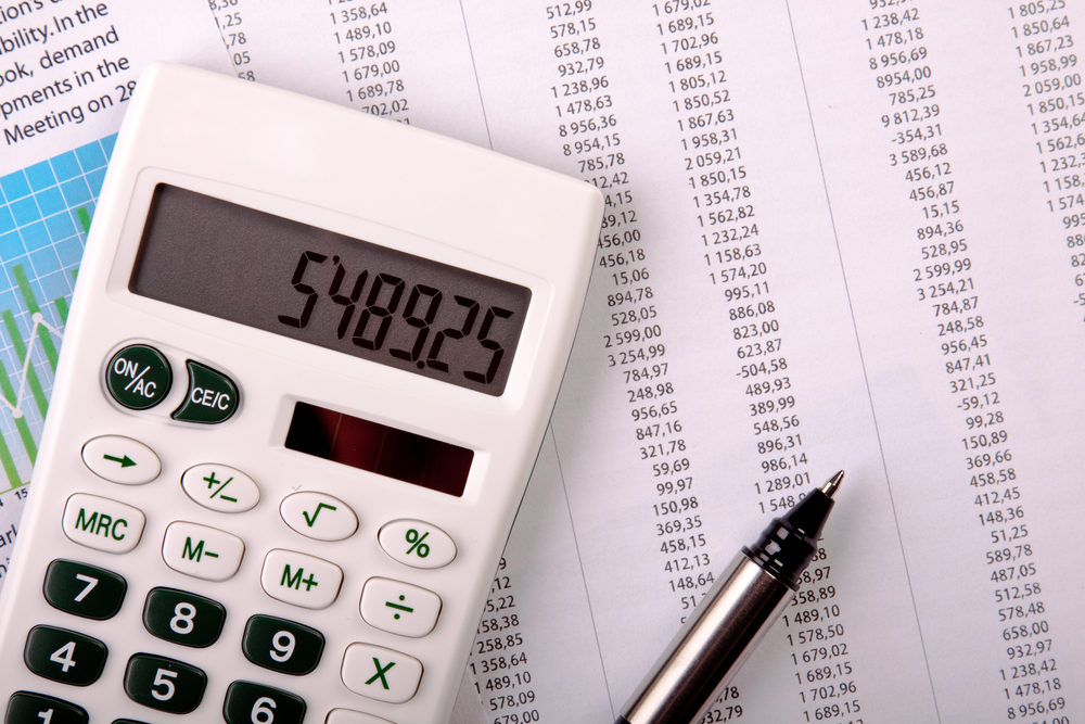 A calculator and pen sit on top of a bank statement.