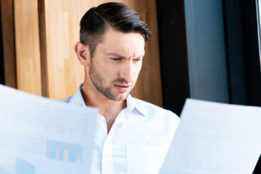 A person looking confused while looking at financial documents.