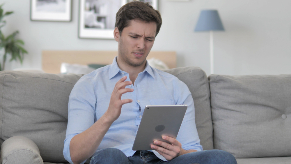 An person looks upset as they read off of their tablet.
