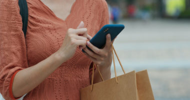 A person holding a shopping bag while using their phone.