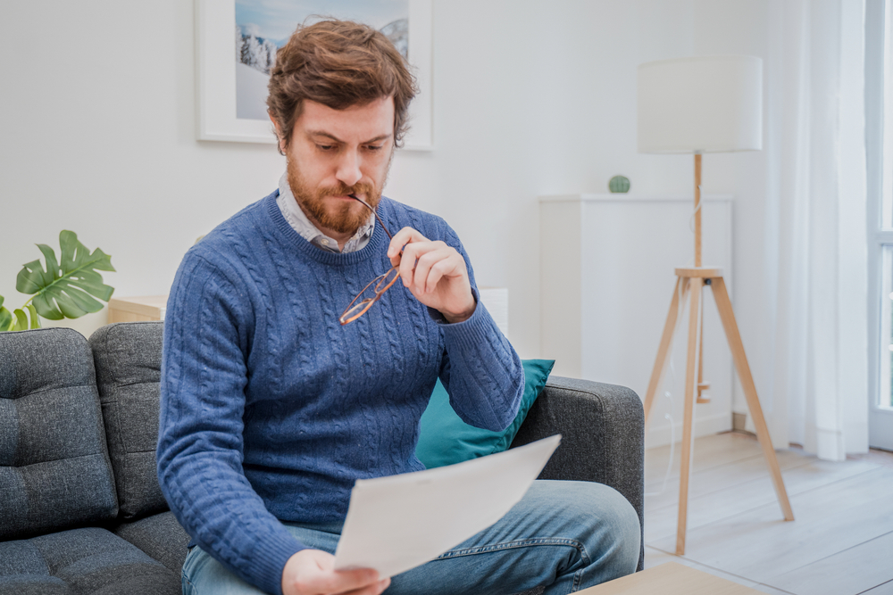 A person looking frustrated while reading a financial document.