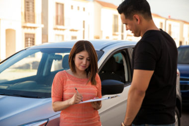 A person signing a car lease at a dealership.