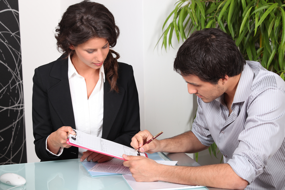 A loan officer holding a document for a client to sign.