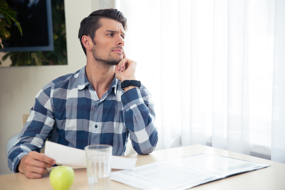 A person looking worried as they hold financial documents.