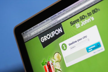 A computer screen displays the Groupon home screen.