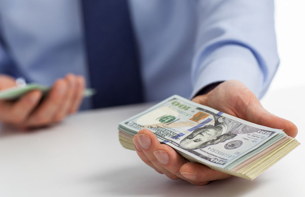 A loan officer offering money to a person behind the camera.