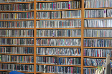 A large collection of CDs, DVDs, and video games sitting on bookshelves.