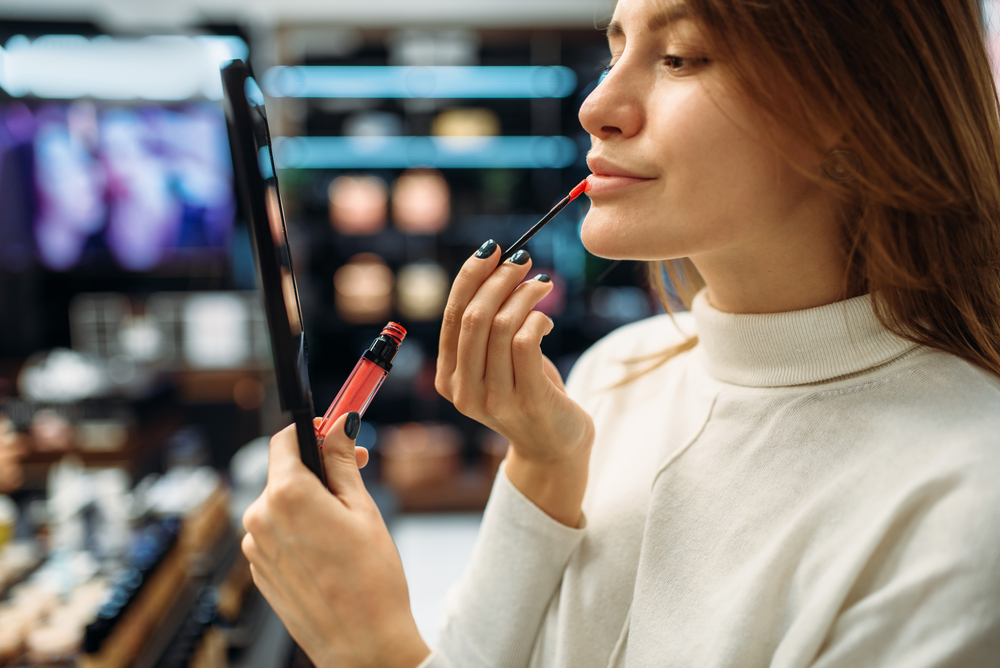 A person testing lip liner at a makeup shop.
